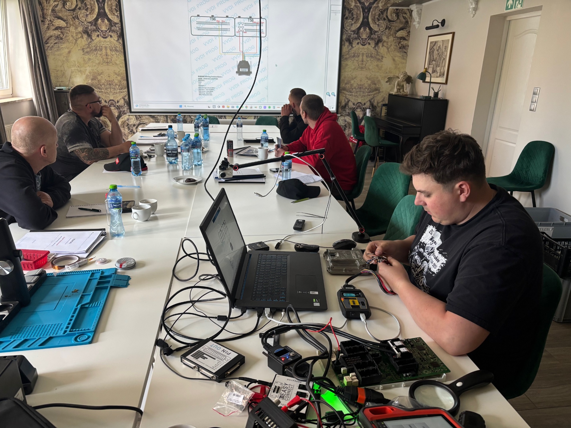Stanowisko VVDI Prog – kursant TOMSAD podłącza adapter BOSCH ECU według schematu wyświetlanego na ekranie, 17 maja 2026